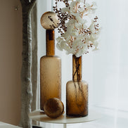 Hand-blown amber glass bottle with an ice-textured finish and rounded stopper for mid-century and contemporary luxury interiors.