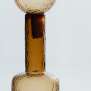 Hand-blown amber glass bottle with an ice-textured finish and rounded stopper for mid-century and contemporary luxury interiors.