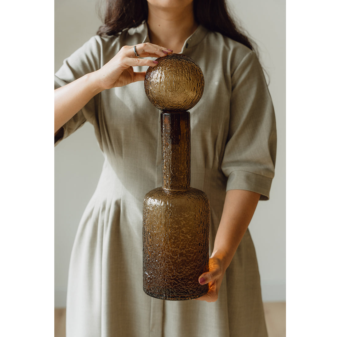 Hand-blown amber glass bottle with an ice-textured finish and rounded stopper for mid-century and contemporary luxury interiors.