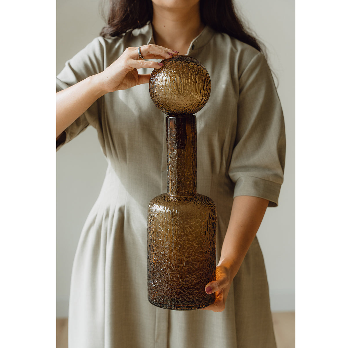 Hand-blown amber glass bottle with an ice-textured finish and rounded stopper for mid-century and contemporary luxury interiors.