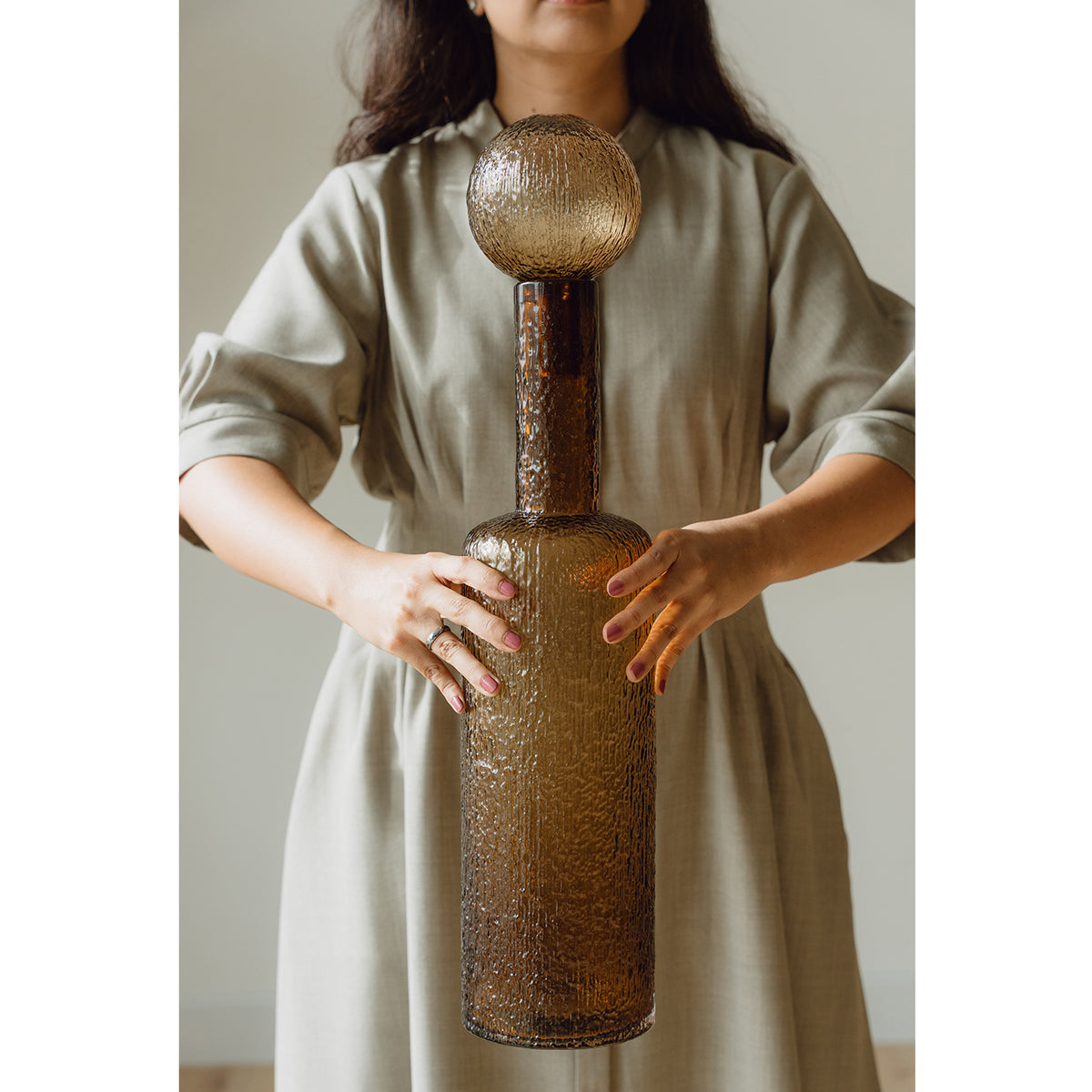 Hand-blown amber glass bottle with an ice-textured finish and rounded stopper for mid-century and contemporary luxury interiors.