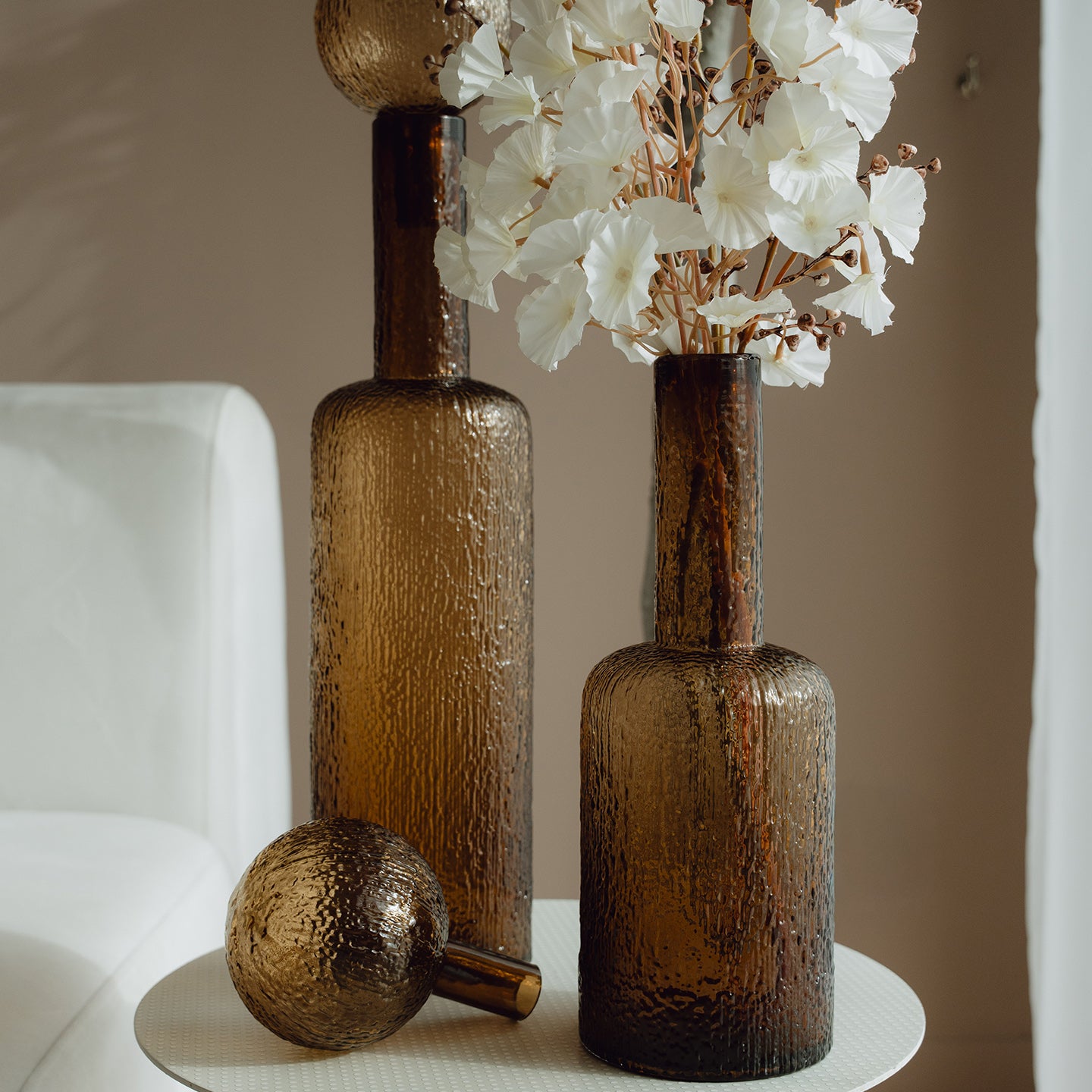 Hand-blown amber glass bottle with an ice-textured finish and rounded stopper for mid-century and contemporary luxury interiors.