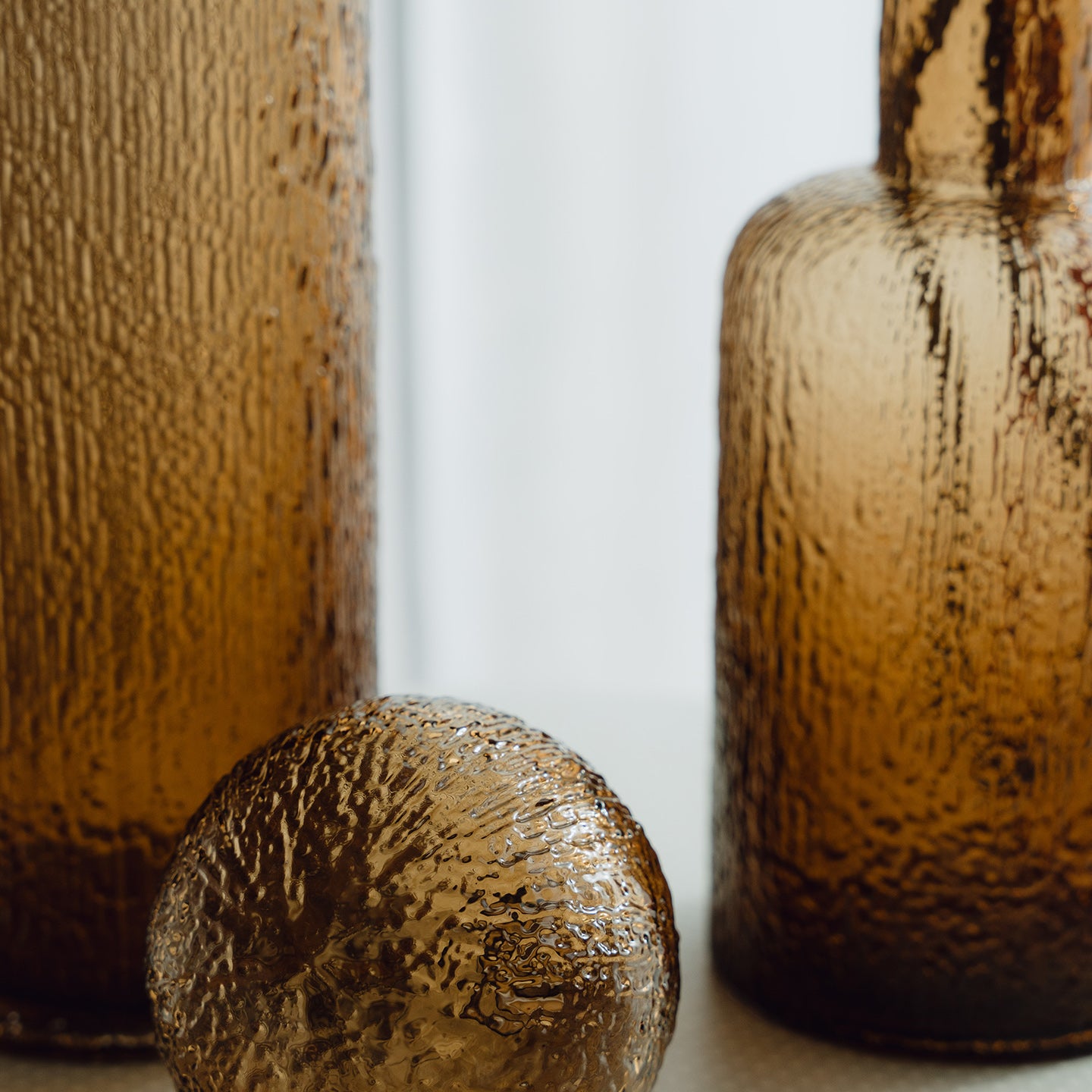 Hand-blown amber glass bottle with an ice-textured finish and rounded stopper for mid-century and contemporary luxury interiors.