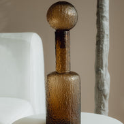 Hand-blown amber glass bottle with an ice-textured finish and rounded stopper for mid-century and contemporary luxury interiors.