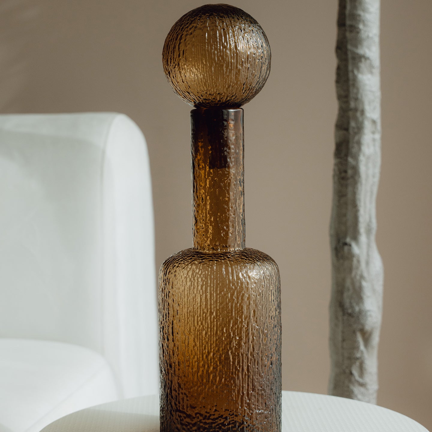 Hand-blown amber glass bottle with an ice-textured finish and rounded stopper for mid-century and contemporary luxury interiors.