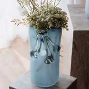 Frosted light blue decorative glass vase with a sculptural flowing silhouette for contemporary and luxury interiors.