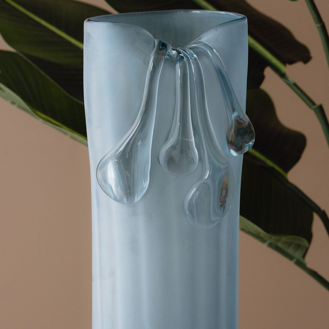 Frosted light blue decorative glass vase with a sculptural flowing silhouette for contemporary and luxury interiors.