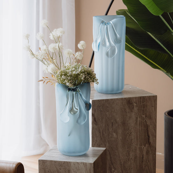 Frosted light blue decorative glass vase with a sculptural flowing silhouette for contemporary and luxury interiors.