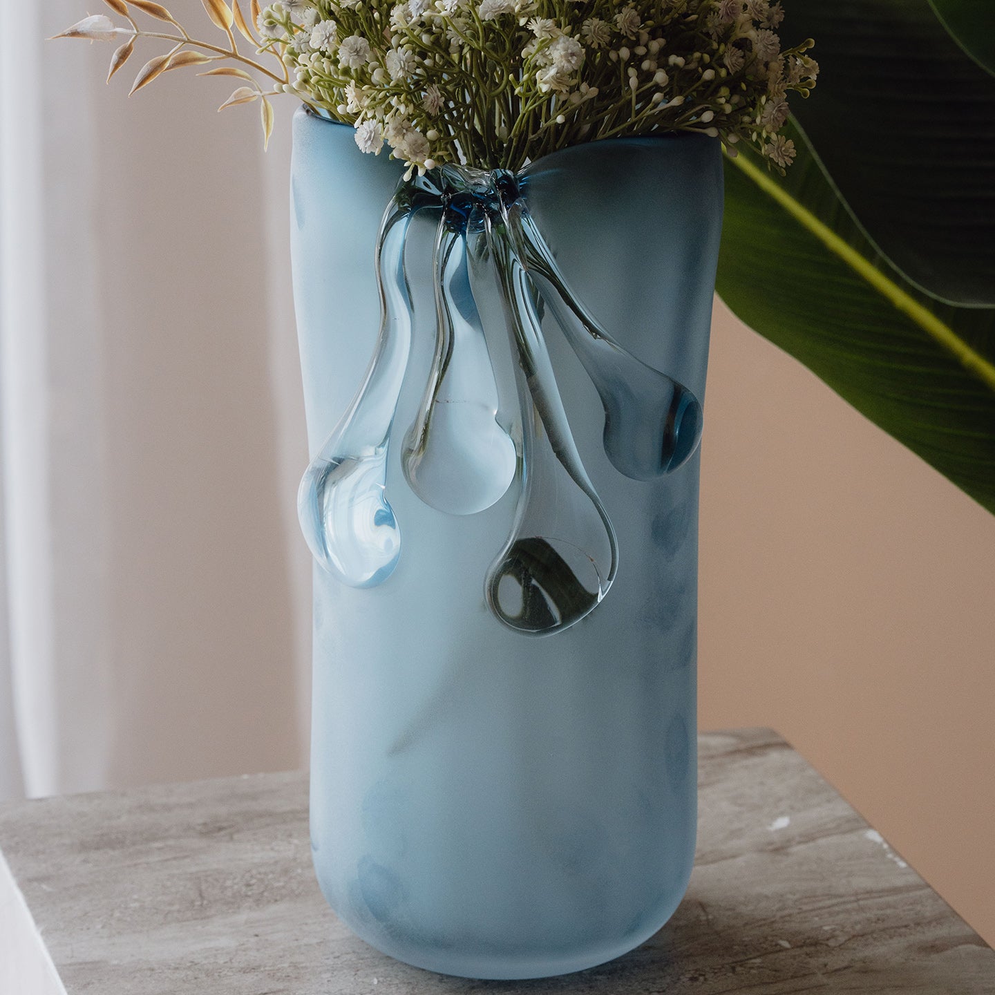 Frosted light blue decorative glass vase with a sculptural flowing silhouette for contemporary and luxury interiors.