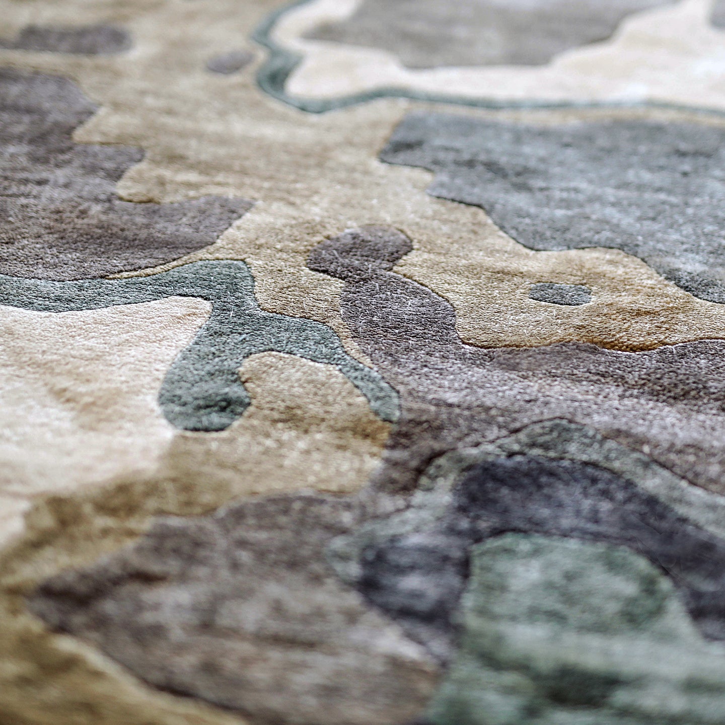 Handmade bamboo silk rug with textured organic motifs in soft blue, deep green, and neutral tones inspired by flowing water.