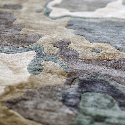 Handmade bamboo silk rug with textured organic motifs in soft blue, deep green, and neutral tones inspired by flowing water.