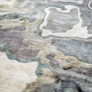 Handmade bamboo silk rug with textured organic motifs in soft blue, deep green, and neutral tones inspired by flowing water.