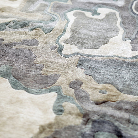 Handmade bamboo silk rug with textured organic motifs in soft blue, deep green, and neutral tones inspired by flowing water.