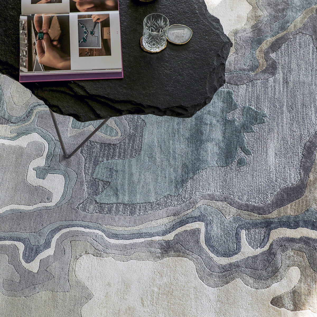 Handmade bamboo silk rug with textured organic motifs in soft blue, deep green, and neutral tones inspired by flowing water.