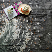 Handmade botanical rug inspired by UAE palm leaves with delicate leaf motifs fading into soft scattered flecks of colour.
