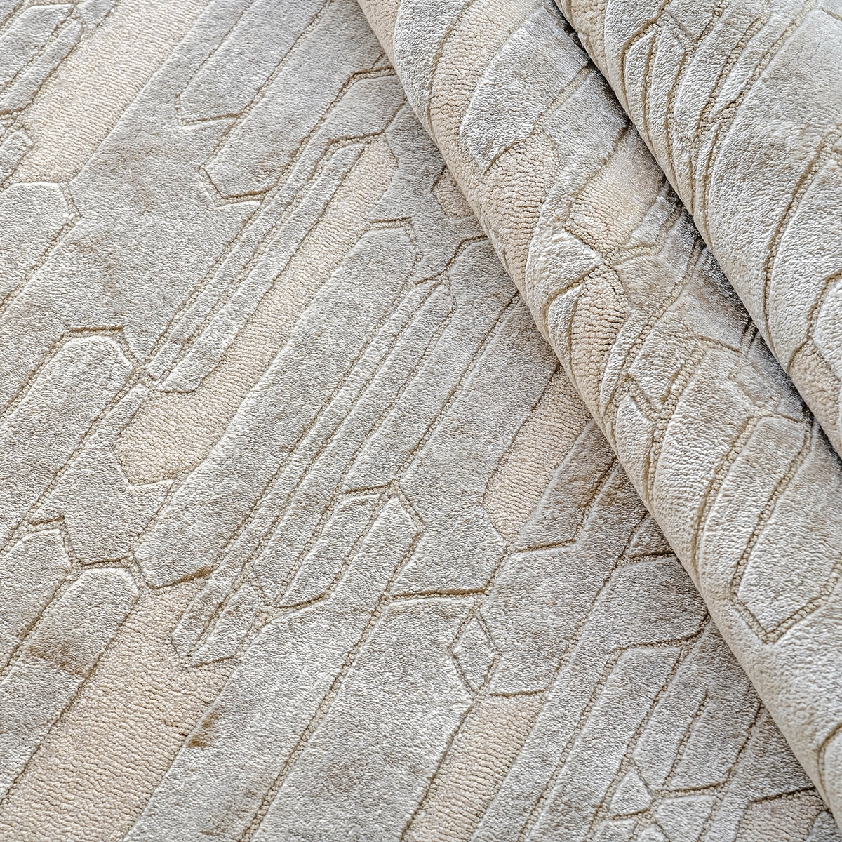 Handmade geometric rug with a textured monotone design and varying pile heights for contemporary luxury interiors.