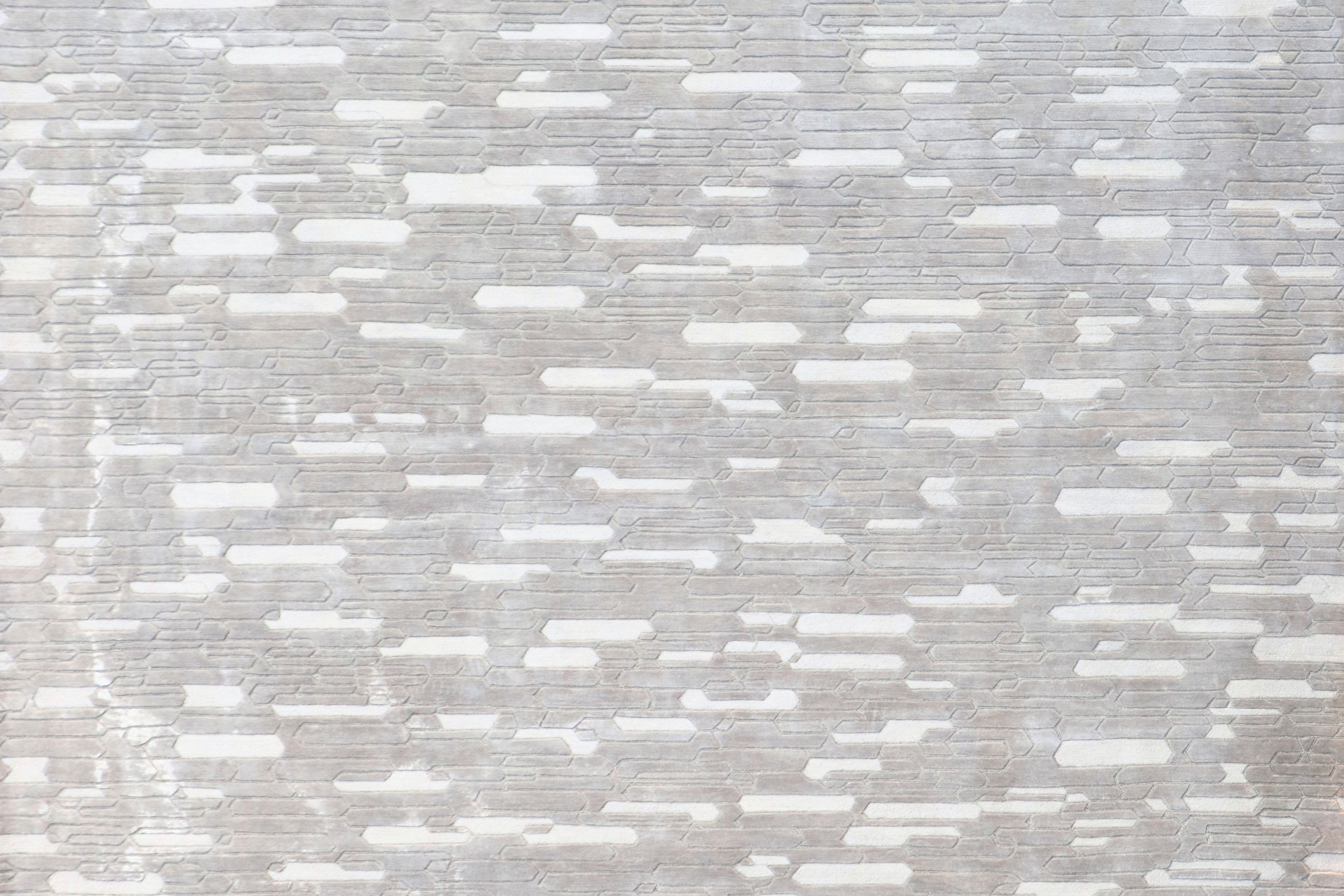 Handmade geometric rug with a textured monotone design and varying pile heights for contemporary luxury interiors.