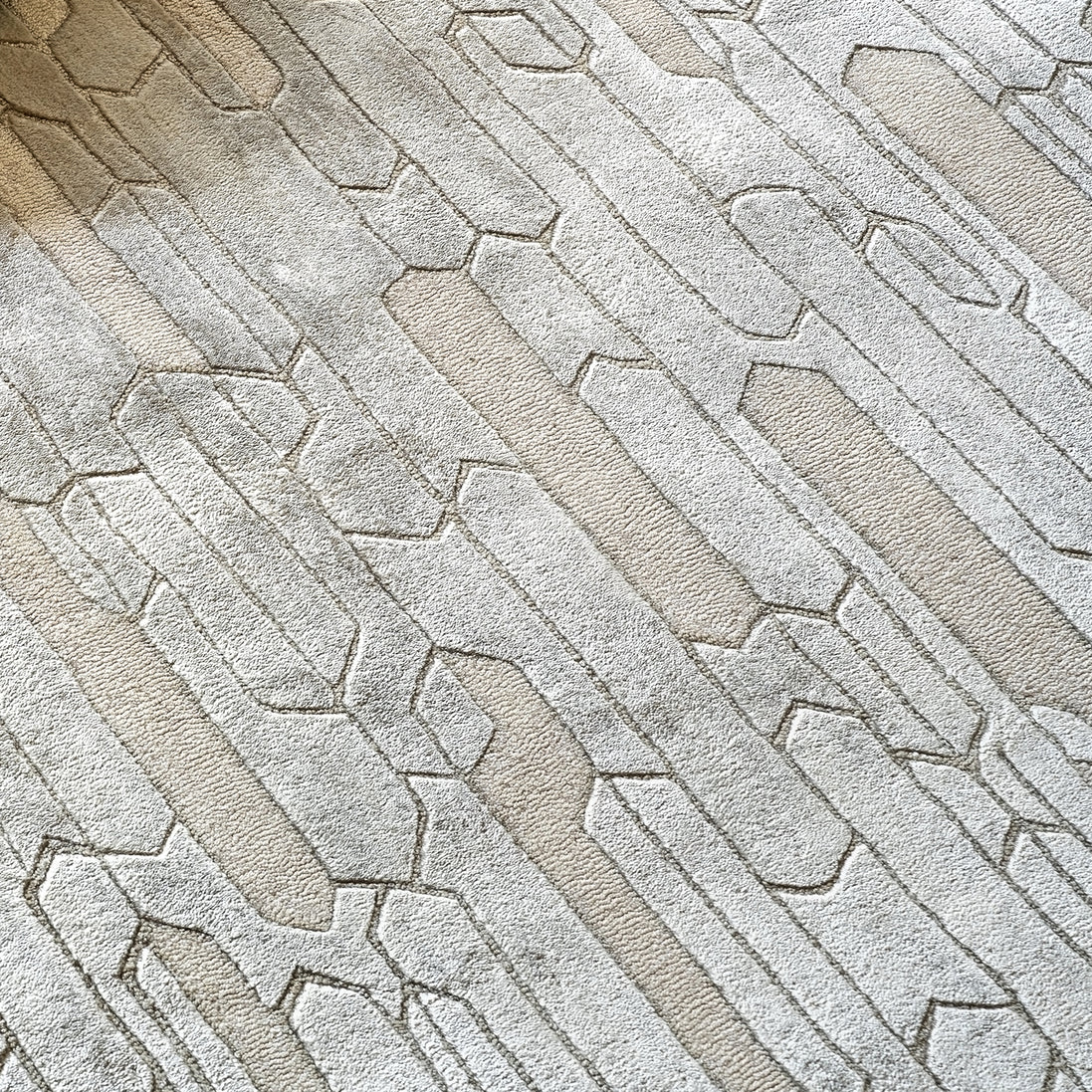 Handmade geometric rug with a textured monotone design and varying pile heights for contemporary luxury interiors.