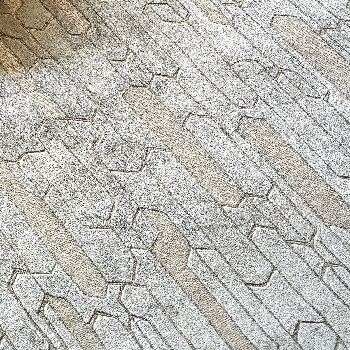 Handmade geometric rug with a textured monotone design and varying pile heights for contemporary luxury interiors.