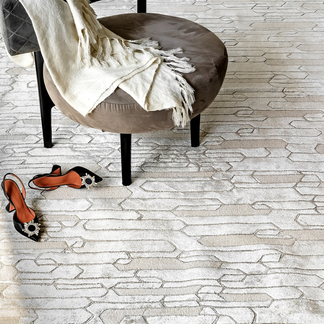 Handmade geometric rug with a textured monotone design and varying pile heights for contemporary luxury interiors.