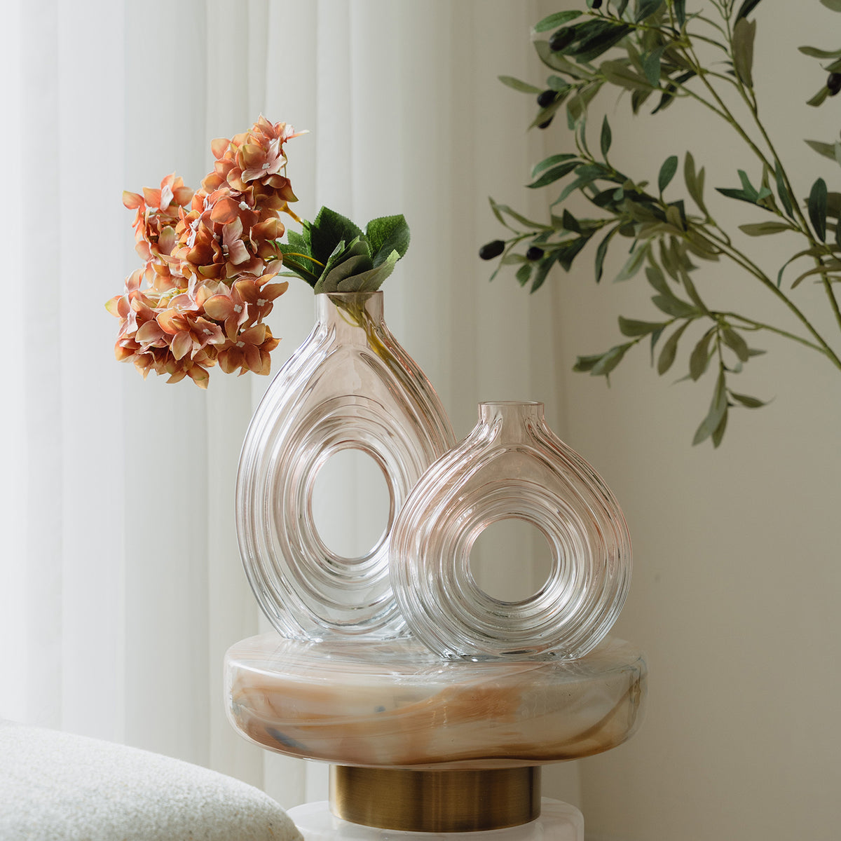 Hand-blown blush glass vase with a sculptural spiral design and flattened silhouette, available in two sizes for modern luxury interiors.