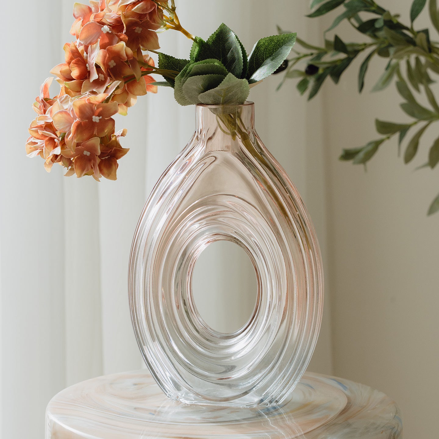 Hand-blown blush glass vase with a sculptural spiral design and flattened silhouette, available in two sizes for modern luxury interiors.