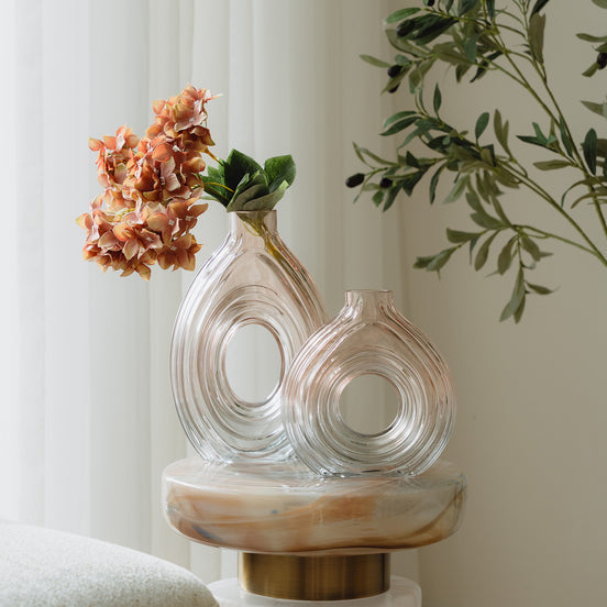 Hand-blown blush glass vase with a sculptural spiral design and flattened silhouette, available in two sizes for modern luxury interiors.