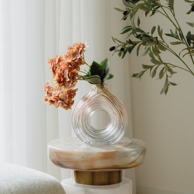 Hand-blown blush glass vase with a sculptural spiral design and flattened silhouette, available in two sizes for modern luxury interiors.