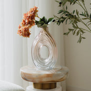 Hand-blown blush glass vase with a sculptural spiral design and flattened silhouette, available in two sizes for modern luxury interiors.