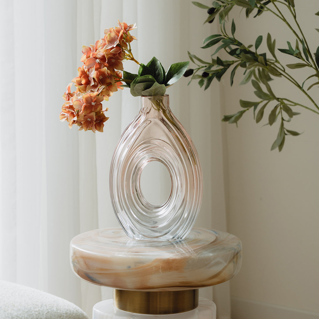 Hand-blown blush glass vase with a sculptural spiral design and flattened silhouette, available in two sizes for modern luxury interiors.