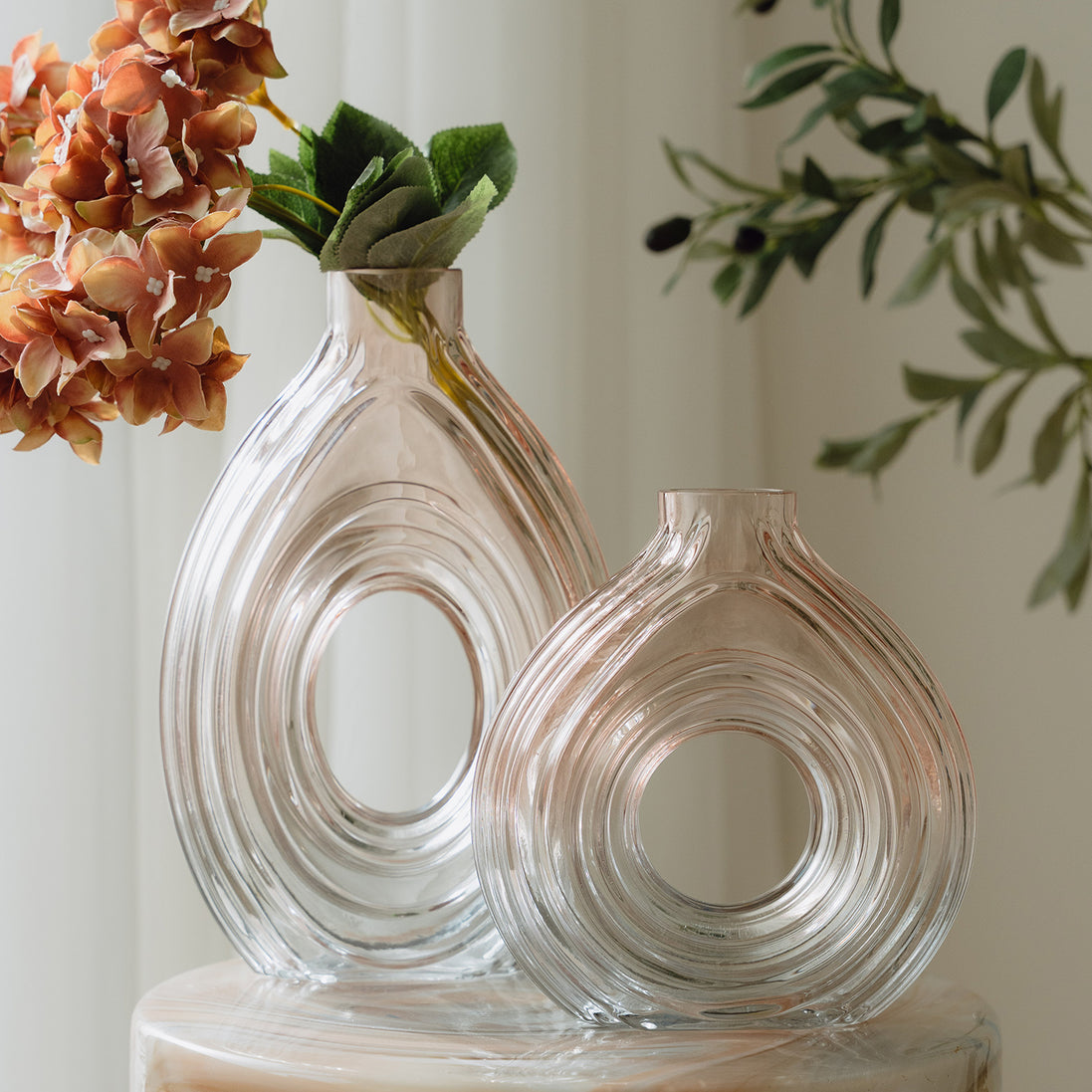 Hand-blown blush glass vase with a sculptural spiral design and flattened silhouette, available in two sizes for modern luxury interiors.
