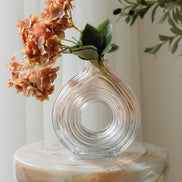 Hand-blown blush glass vase with a sculptural spiral design and flattened silhouette, available in two sizes for modern luxury interiors.
