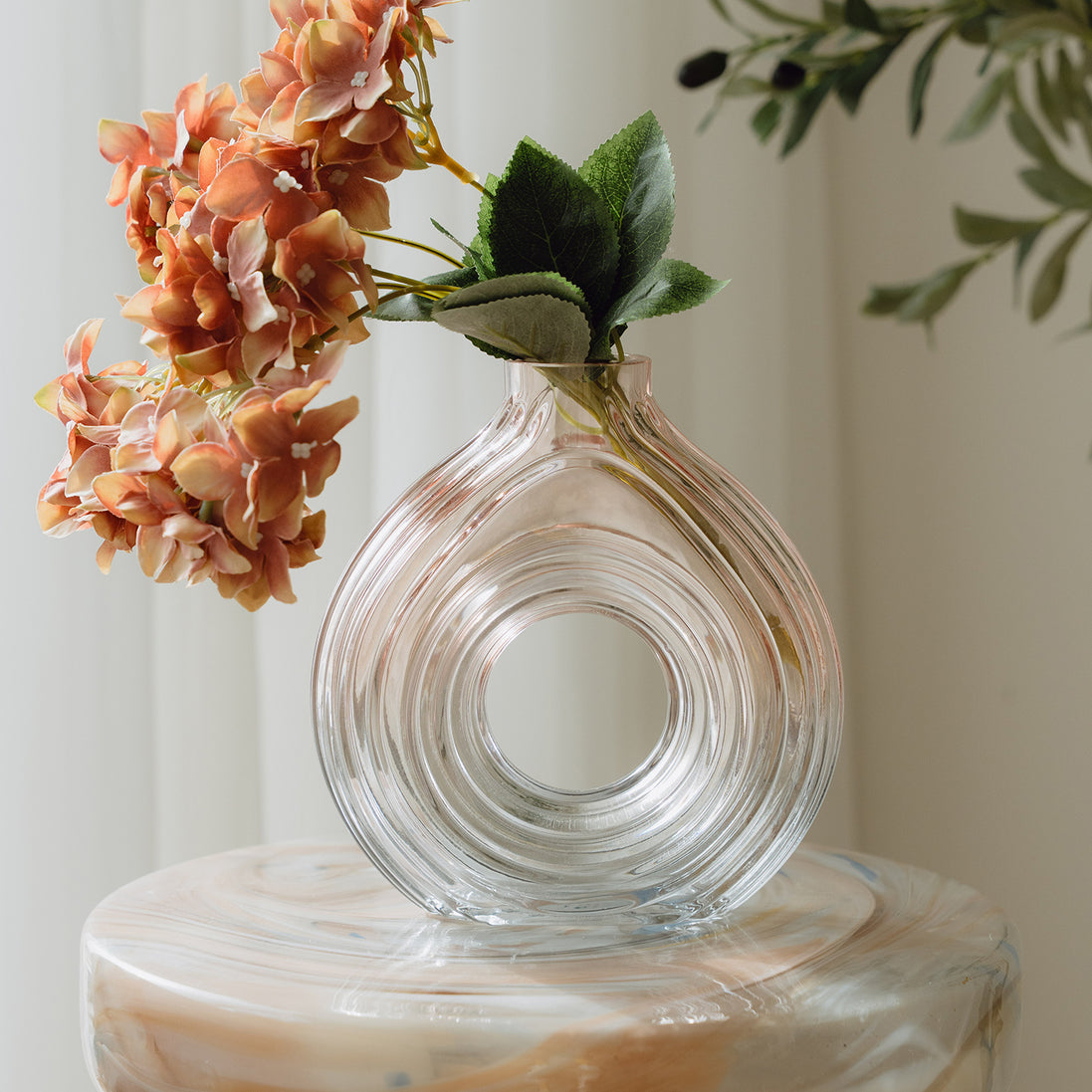 Hand-blown blush glass vase with a sculptural spiral design and flattened silhouette, available in two sizes for modern luxury interiors.