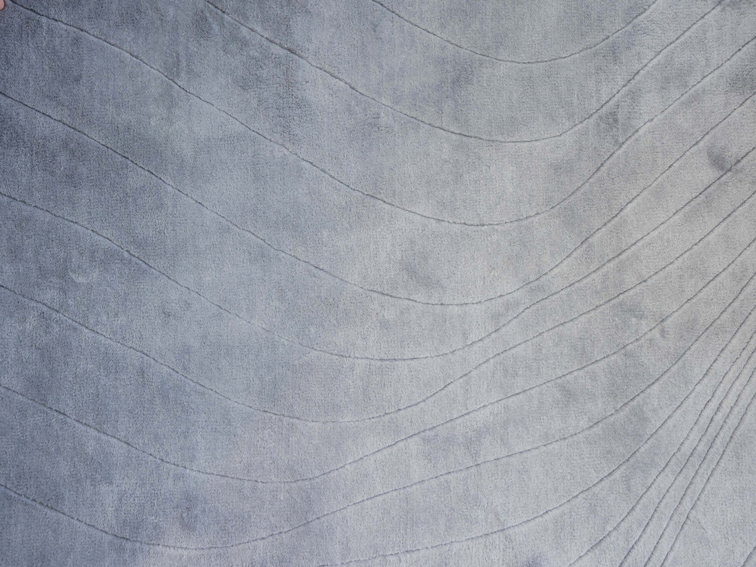 Handmade 100% Tencel rug with embossed wave carvings, subtle tonal texture, and a silky finish for modern luxury interiors.