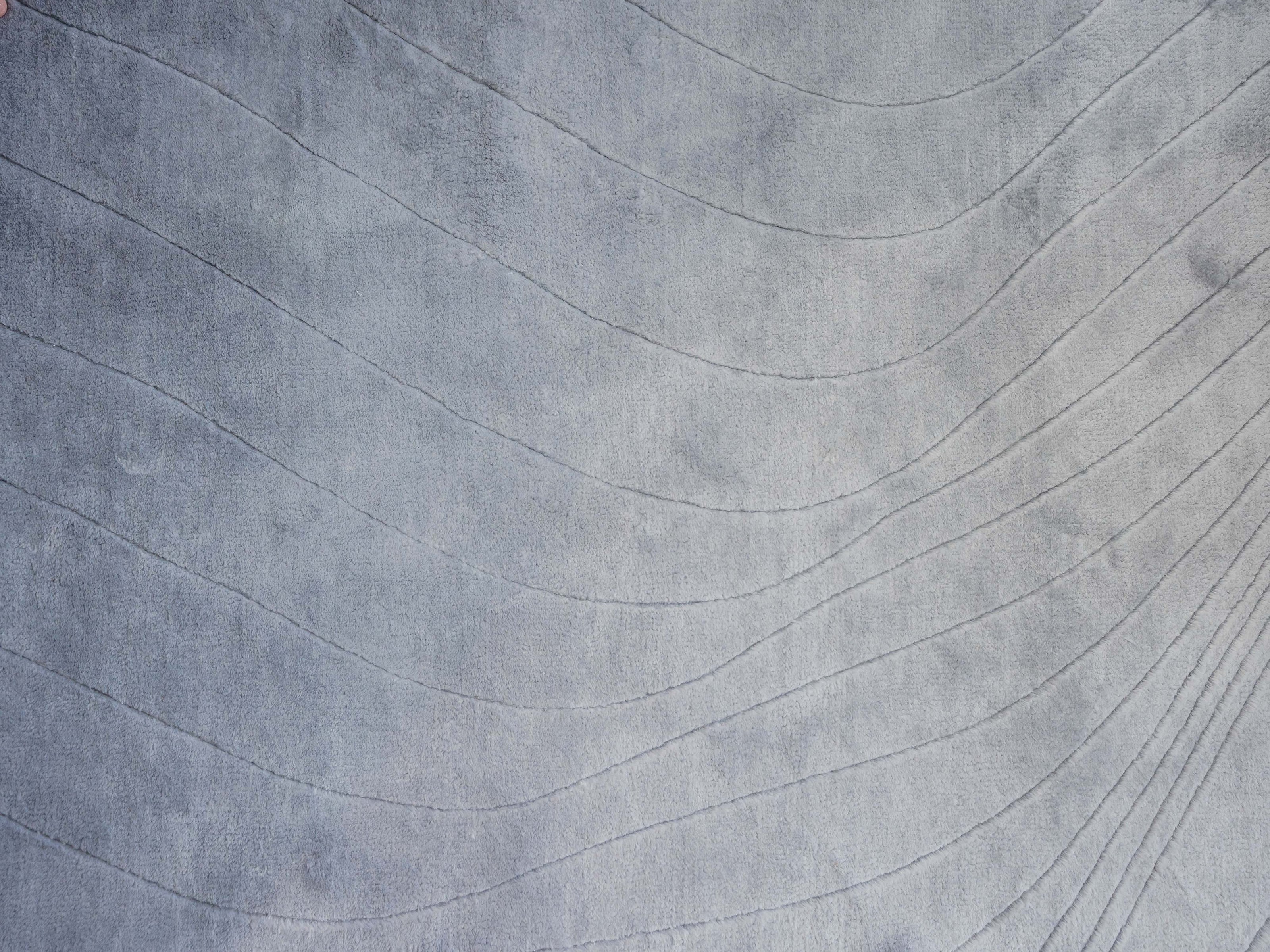 Handmade 100% Tencel rug with embossed wave carvings, subtle tonal texture, and a silky finish for modern luxury interiors.