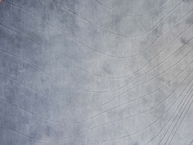Handmade 100% Tencel rug with embossed wave carvings, subtle tonal texture, and a silky finish for modern luxury interiors.