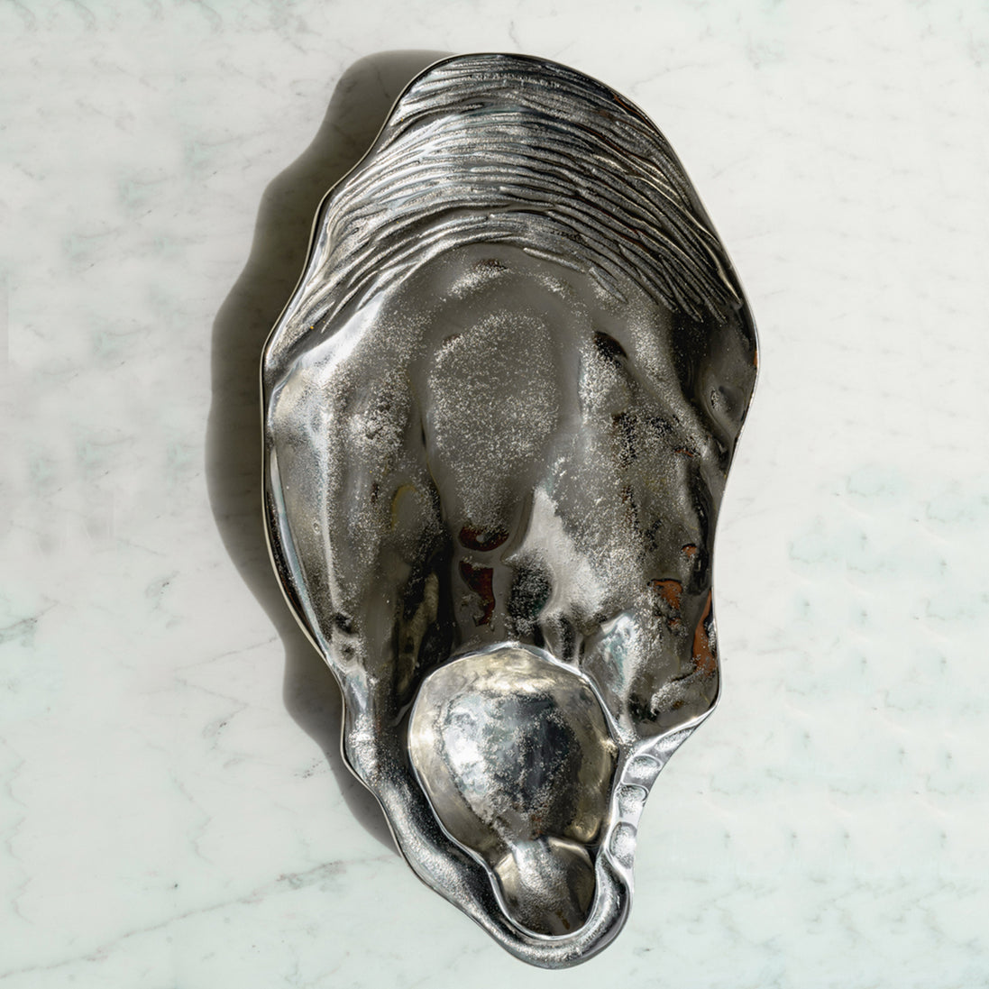 Seashell silver decorative platter with intricate shell design, coastal-inspired luxury home décor accent.