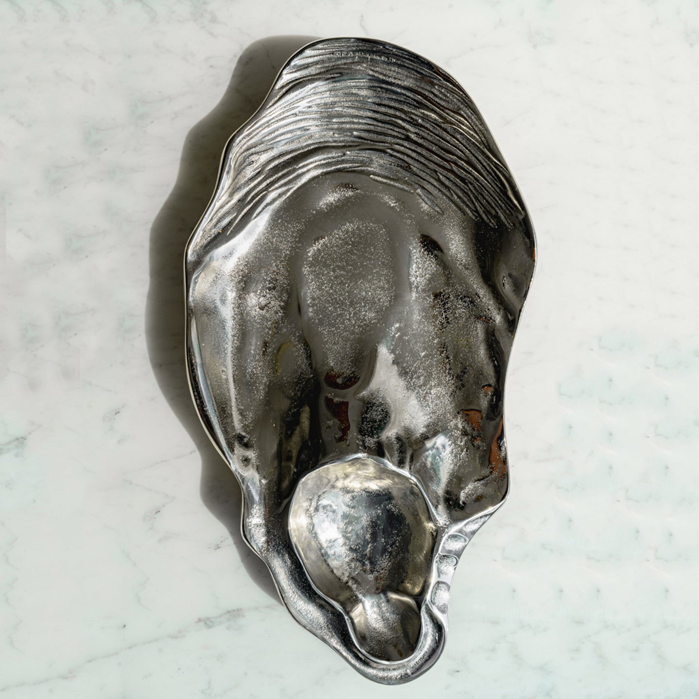 Seashell silver decorative platter with intricate shell design, coastal-inspired luxury home décor accent.