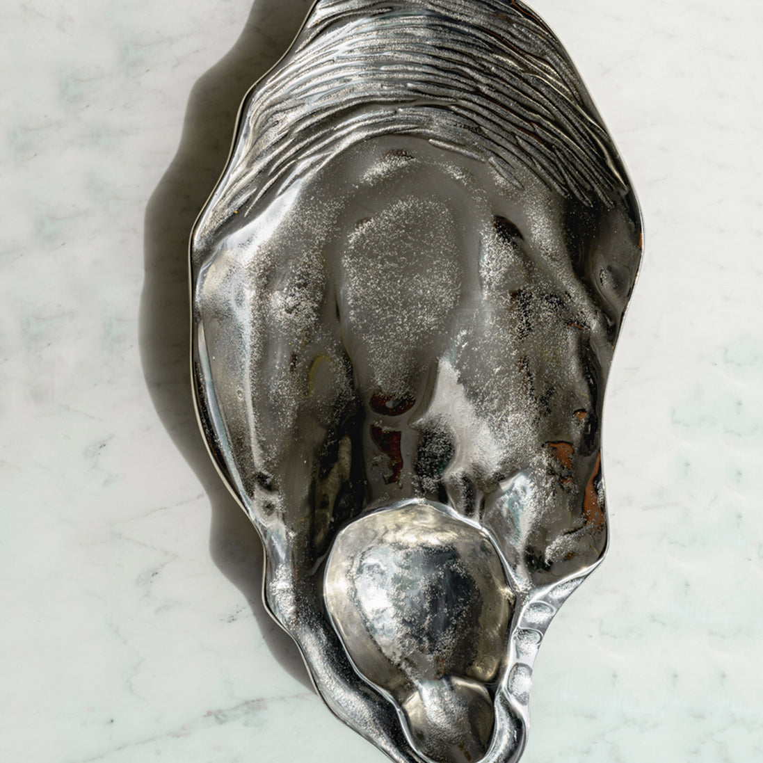 Seashell silver decorative platter with intricate shell design, coastal-inspired luxury home décor accent.