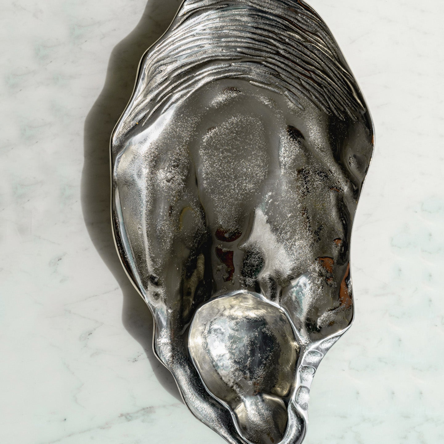 Seashell silver decorative platter with intricate shell design, coastal-inspired luxury home décor accent.