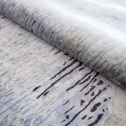 Handmade abstract rug inspired by blue stone and ocean waves with a flowing wave pattern, soft sheen, and velvety texture.