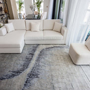 Handmade abstract rug inspired by blue stone and ocean waves with a flowing wave pattern, soft sheen, and velvety texture.