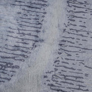 Handmade abstract rug inspired by blue stone and ocean waves with a flowing wave pattern, soft sheen, and velvety texture.
