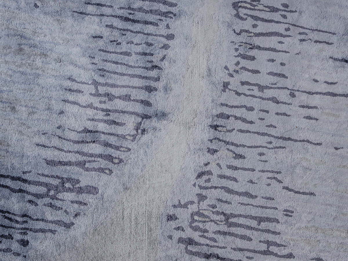 Handmade abstract rug inspired by blue stone and ocean waves with a flowing wave pattern, soft sheen, and velvety texture.