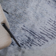 Handmade abstract rug inspired by blue stone and ocean waves with a flowing wave pattern, soft sheen, and velvety texture.