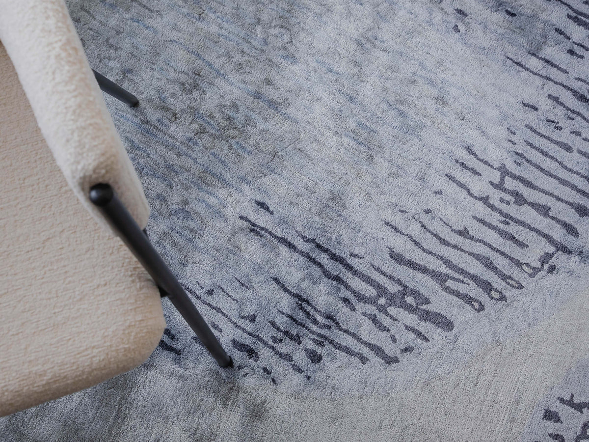 Handmade abstract rug inspired by blue stone and ocean waves with a flowing wave pattern, soft sheen, and velvety texture.