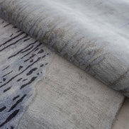 Handmade abstract rug inspired by blue stone and ocean waves with a flowing wave pattern, soft sheen, and velvety texture.