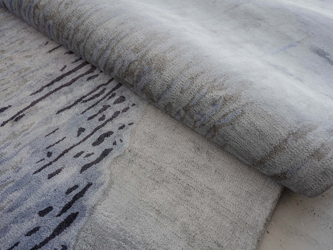 Handmade abstract rug inspired by blue stone and ocean waves with a flowing wave pattern, soft sheen, and velvety texture.