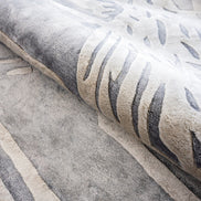 Handmade silver-grey rug with raised ivory abstract patterns and a textured finish for contemporary luxury interiors.