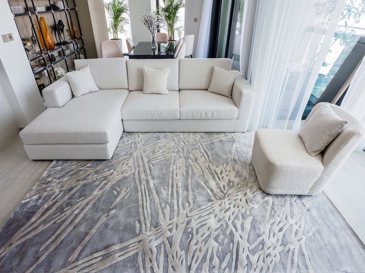 Handmade silver-grey rug with raised ivory abstract patterns and a textured finish for contemporary luxury interiors.